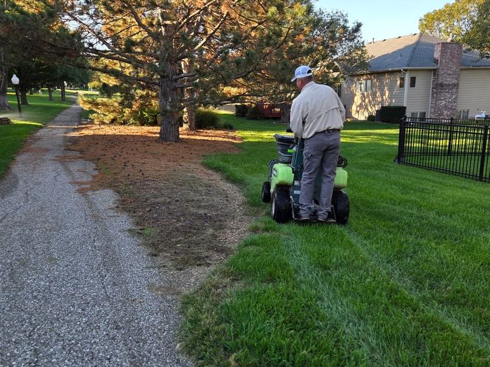 Ride-on spreader-sprayer treating a lawn along a walking path