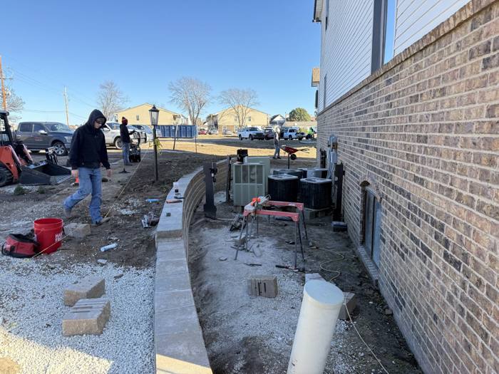 Crew building a block wall beside a building